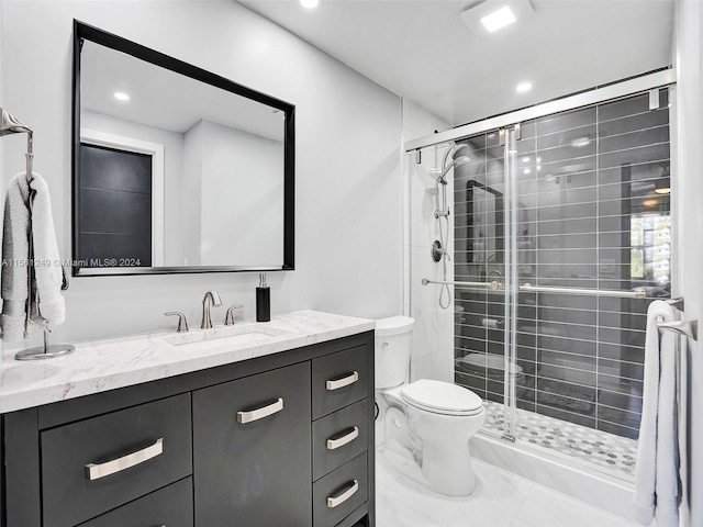 bathroom featuring tile floors, toilet, vanity, and a shower with door