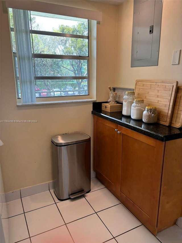 kitchen featuring light tile patterned floors, electric panel, and dark stone counters