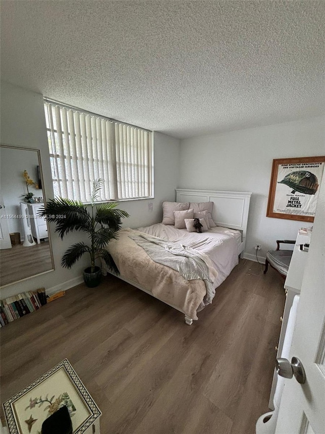 bedroom with a textured ceiling and dark hardwood / wood-style flooring