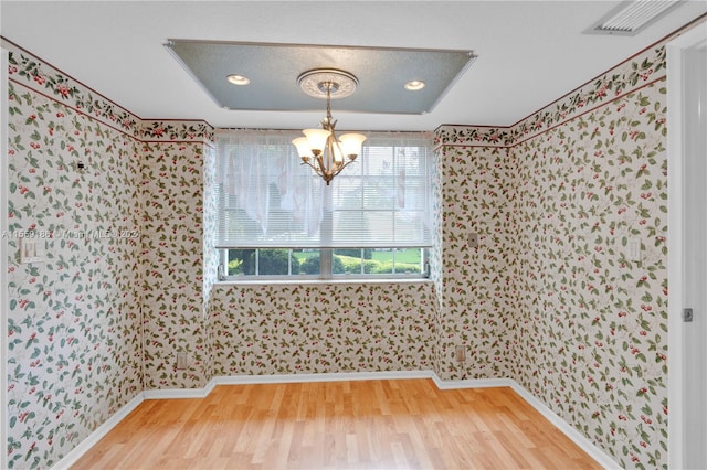 unfurnished dining area featuring wood-type flooring and an inviting chandelier