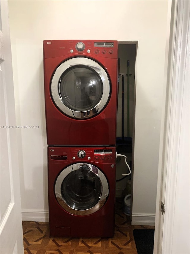 laundry area with dark parquet flooring and stacked washer and dryer