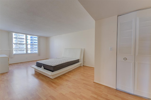 unfurnished bedroom featuring a closet, a textured ceiling, and light hardwood / wood-style floors