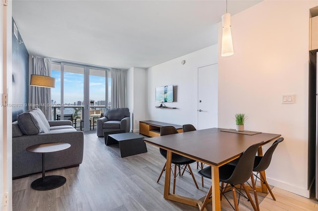 dining space with light hardwood / wood-style flooring and a wall of windows