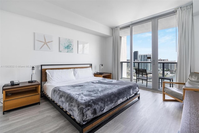 bedroom with wood-type flooring and expansive windows