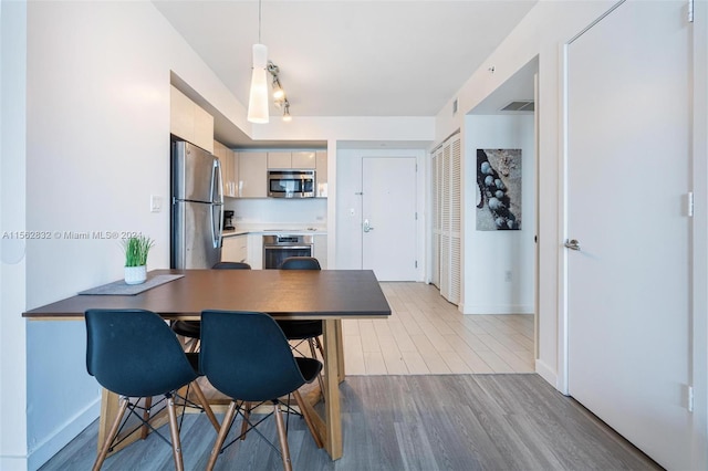 kitchen with hanging light fixtures, light hardwood / wood-style flooring, and stainless steel appliances