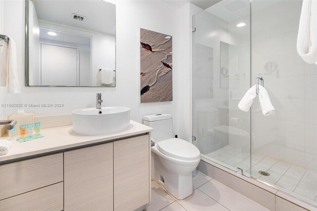 bathroom with a shower with door, toilet, tile flooring, and vanity