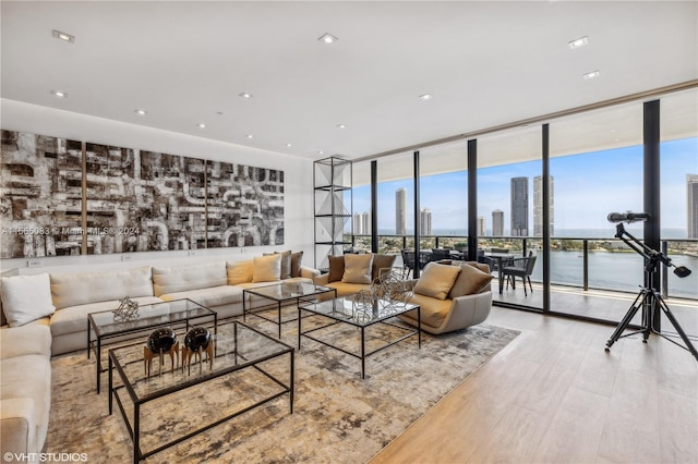 living room with floor to ceiling windows, a water view, and light wood-type flooring