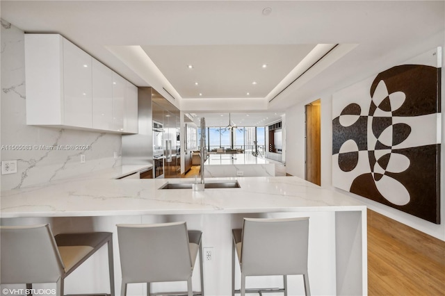 kitchen with a breakfast bar, a raised ceiling, and light stone countertops