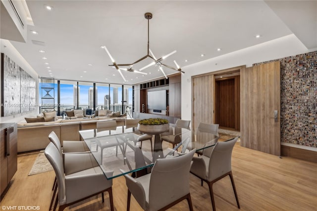 dining room with a chandelier, floor to ceiling windows, and light hardwood / wood-style flooring