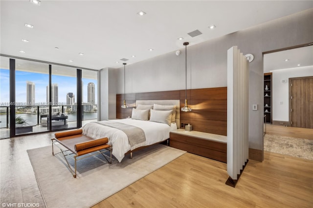 bedroom featuring a wall of windows, light hardwood / wood-style floors, and access to exterior