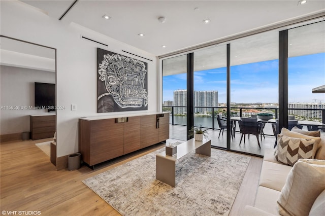 living room featuring floor to ceiling windows, light hardwood / wood-style flooring, and a water view