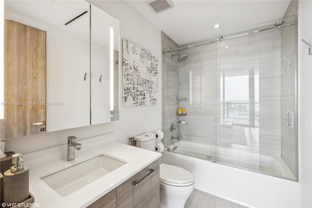 full bathroom with tile floors, toilet, bath / shower combo with glass door, and vanity