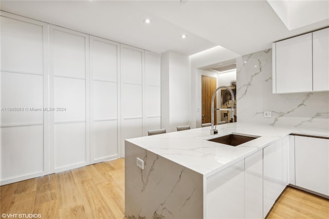 kitchen featuring light hardwood / wood-style flooring, white cabinetry, and light stone counters