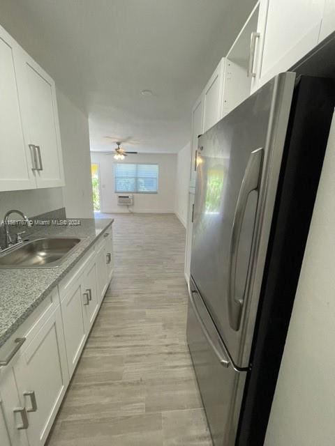 kitchen with stainless steel fridge, ceiling fan, sink, white cabinets, and light wood-type flooring