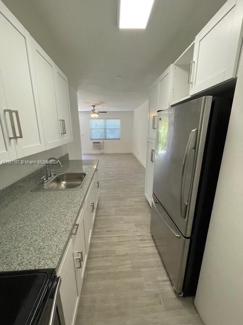 kitchen featuring stainless steel fridge, sink, ceiling fan, range, and light wood-type flooring