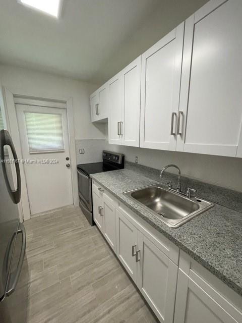 kitchen with sink, white cabinets, light hardwood / wood-style floors, and electric range