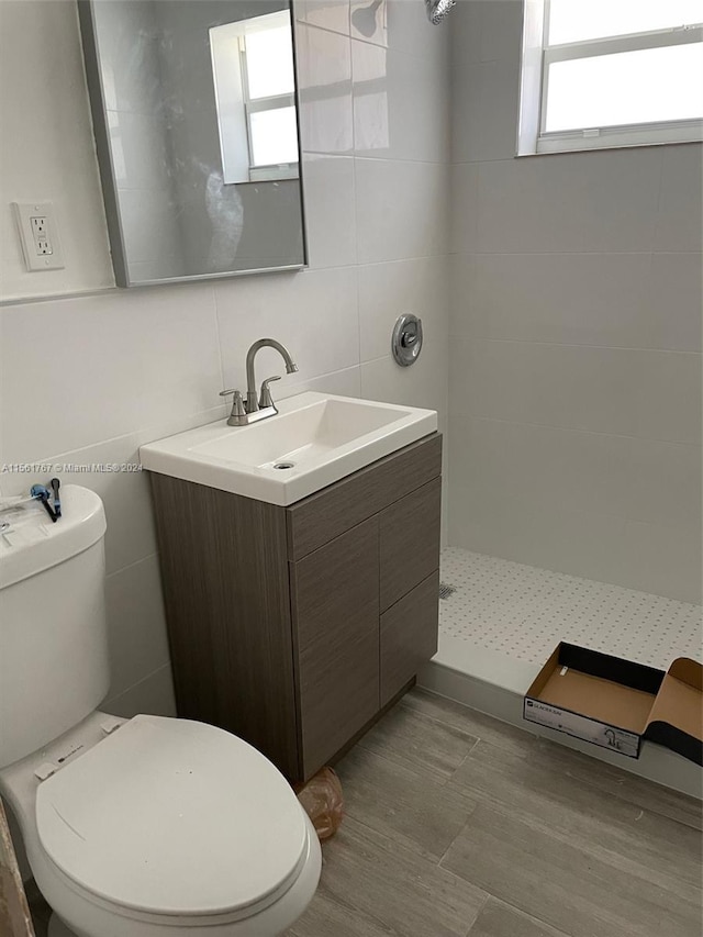 bathroom featuring toilet, tile flooring, vanity, and tile walls