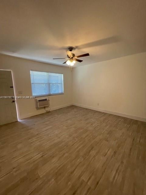 unfurnished room with an AC wall unit, dark hardwood / wood-style floors, and ceiling fan