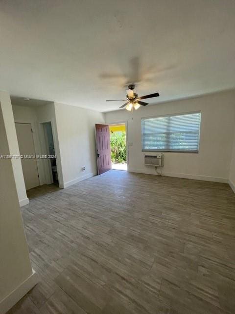 spare room featuring ceiling fan, a wall mounted AC, and dark wood-type flooring