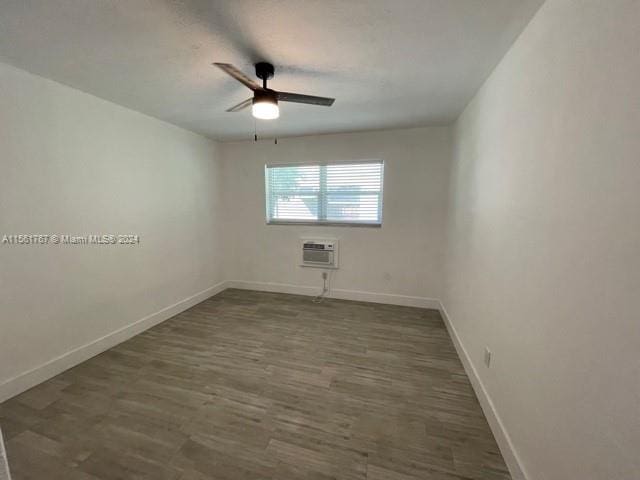 spare room with a wall unit AC, ceiling fan, and dark hardwood / wood-style flooring