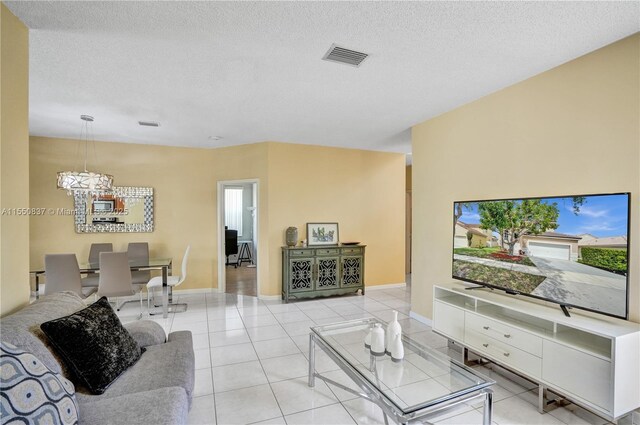 living room featuring a textured ceiling, light tile floors, and an inviting chandelier