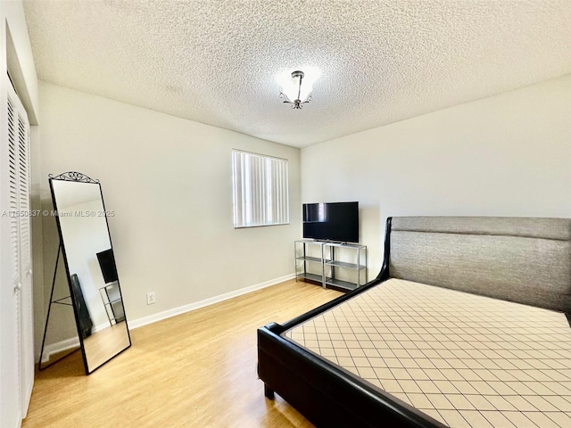 bedroom with a closet, light hardwood / wood-style flooring, ceiling fan, and a textured ceiling