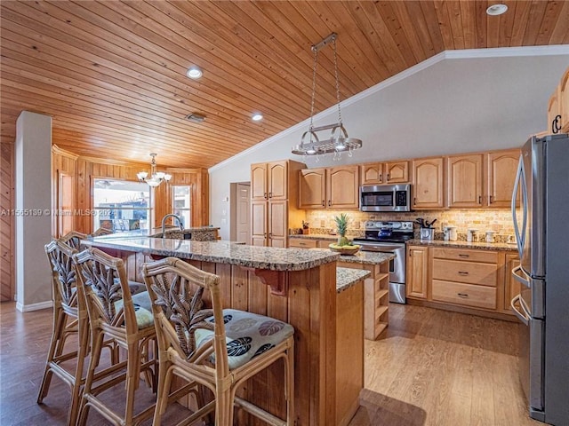 kitchen featuring appliances with stainless steel finishes, a chandelier, light hardwood / wood-style flooring, a center island with sink, and decorative light fixtures