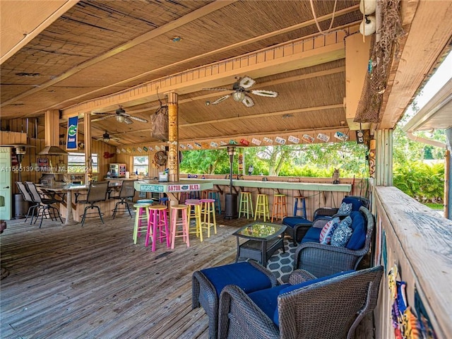 wooden deck featuring ceiling fan, outdoor lounge area, and exterior bar