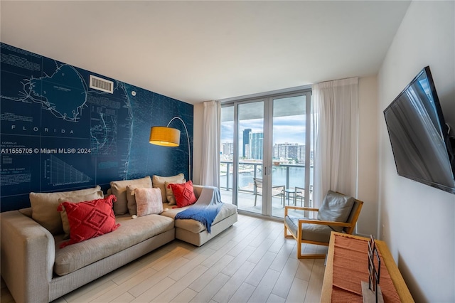 living room with floor to ceiling windows, light hardwood / wood-style floors, french doors, and a water view