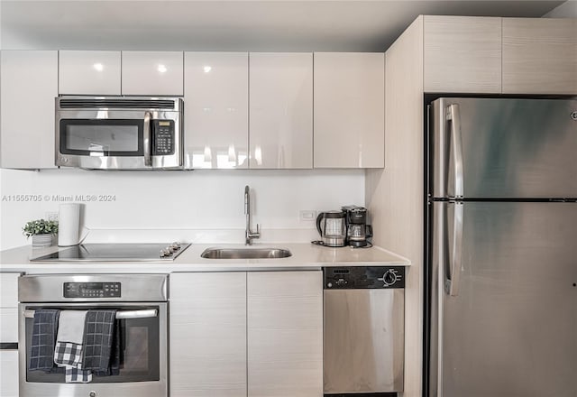 kitchen with stainless steel appliances, white cabinetry, and sink