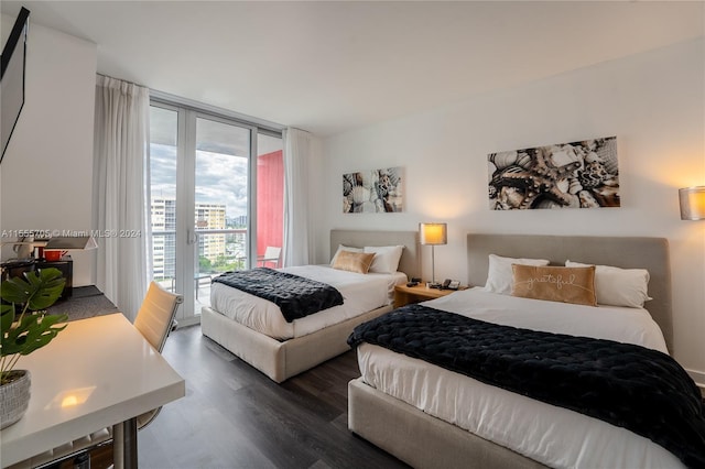 bedroom with dark hardwood / wood-style flooring, access to exterior, and a wall of windows