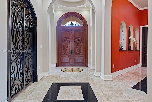 foyer entrance featuring light tile floors and crown molding