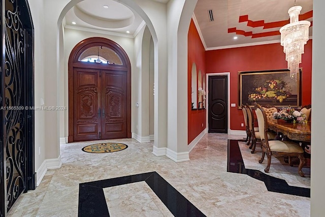 tiled entrance foyer featuring an inviting chandelier and ornamental molding