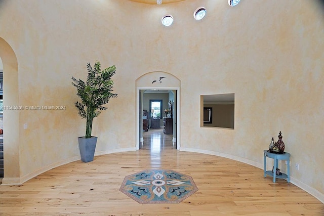 interior space with light hardwood / wood-style flooring and a towering ceiling