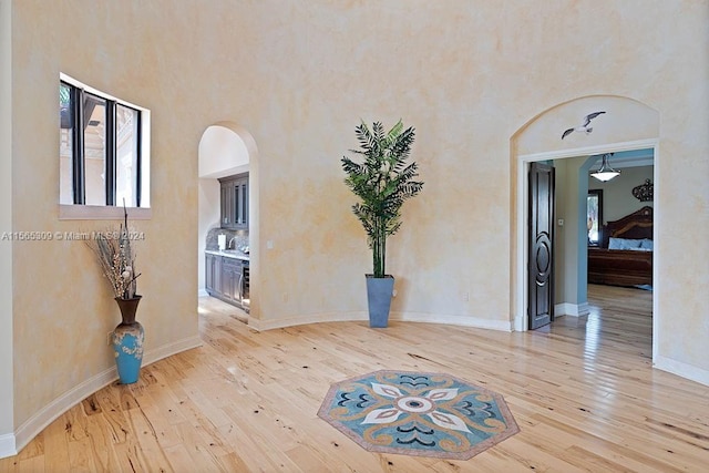 interior space with light wood-type flooring and a towering ceiling