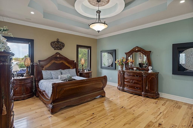 bedroom featuring a raised ceiling, multiple windows, ornamental molding, and light hardwood / wood-style flooring