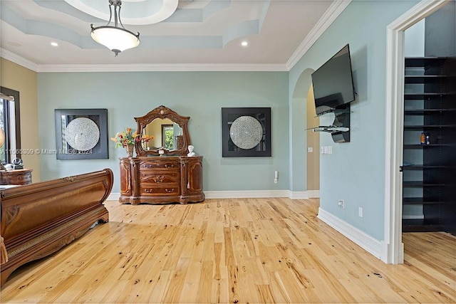 bedroom featuring crown molding, a spacious closet, light wood-type flooring, and a raised ceiling