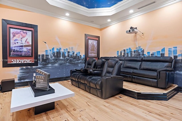 cinema featuring a tray ceiling, light hardwood / wood-style floors, and crown molding