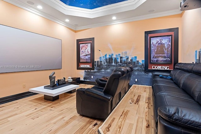 cinema with a tray ceiling, ornamental molding, and light wood-type flooring