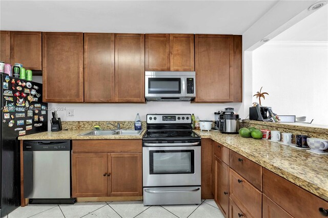 kitchen featuring light stone counters, light tile flooring, appliances with stainless steel finishes, and sink