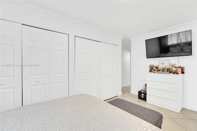 bedroom with light tile flooring, multiple closets, and crown molding