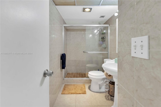 bathroom with a shower with shower door, toilet, and tile floors