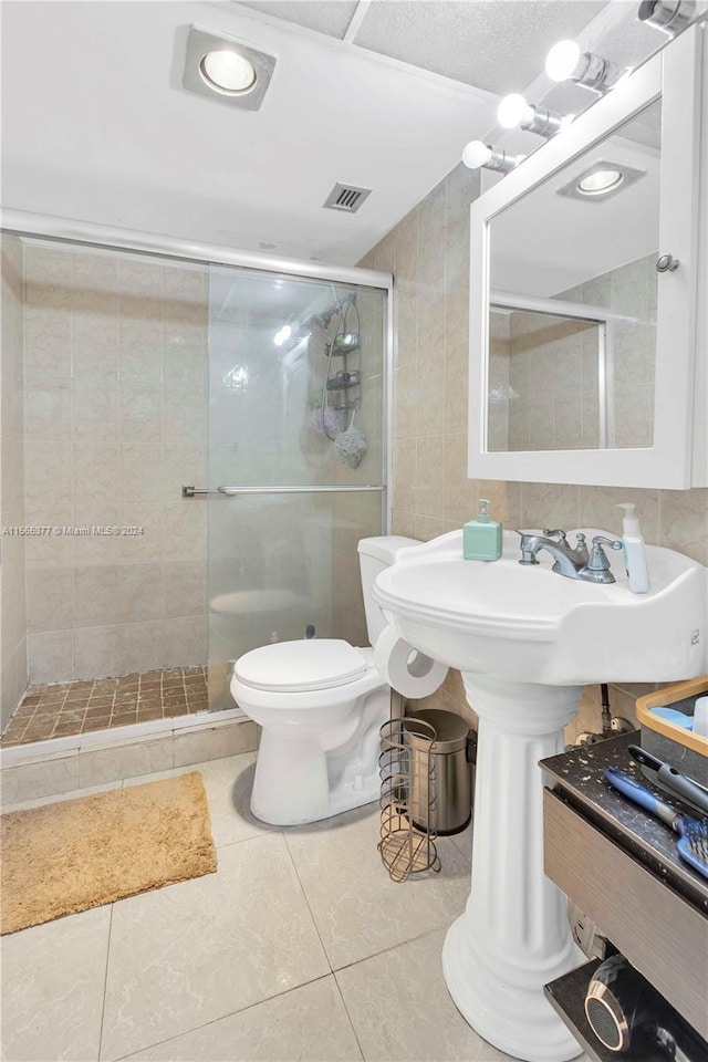 bathroom with toilet, tile floors, and a shower with shower door