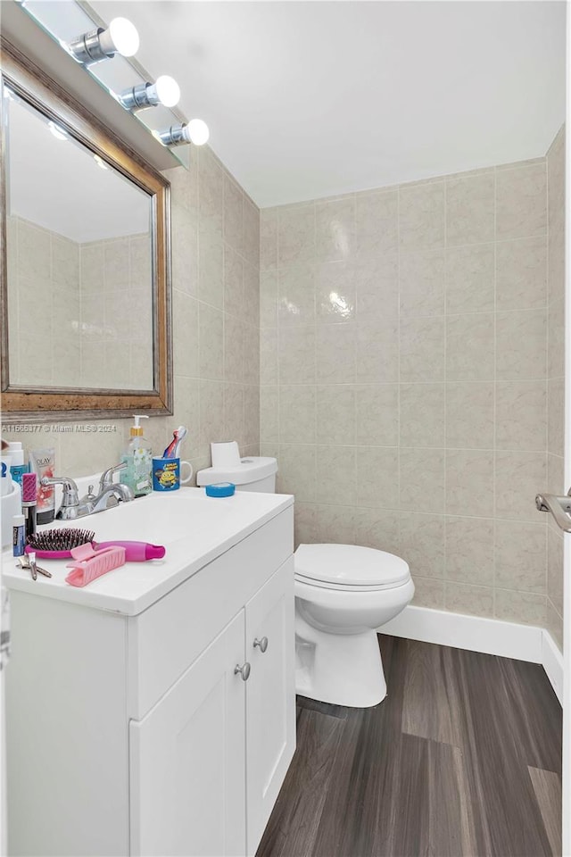 bathroom featuring vanity, wood-type flooring, toilet, and tile walls