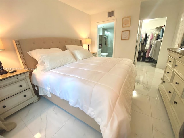 bedroom with a closet, connected bathroom, a spacious closet, and light tile floors