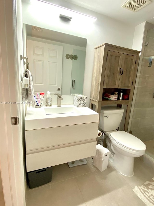 bathroom featuring toilet, tiled shower, tile floors, and vanity