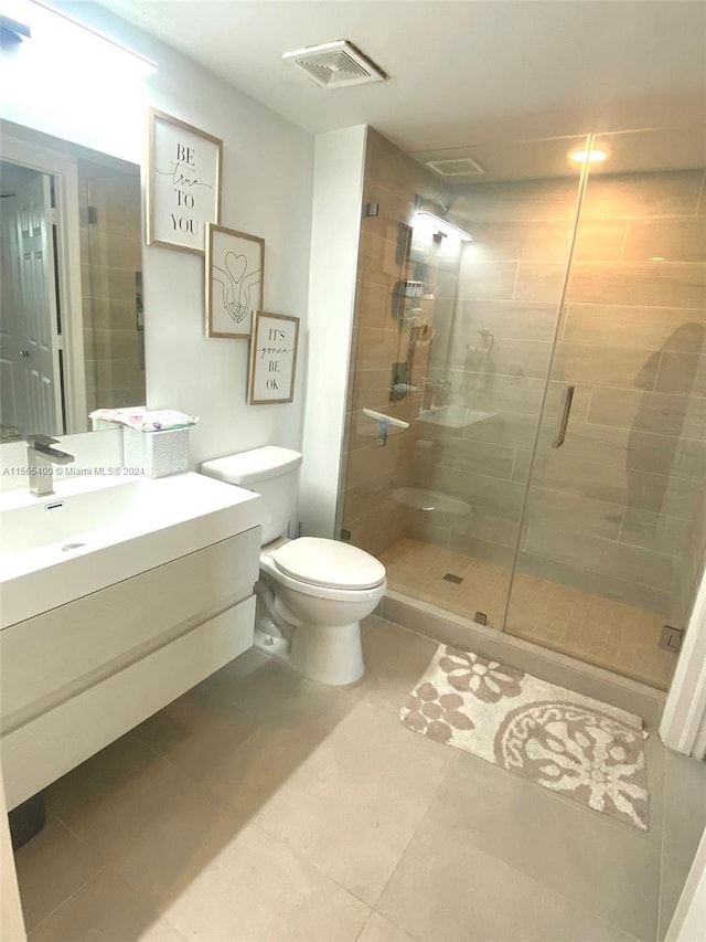 bathroom featuring tile floors, toilet, vanity, and an enclosed shower