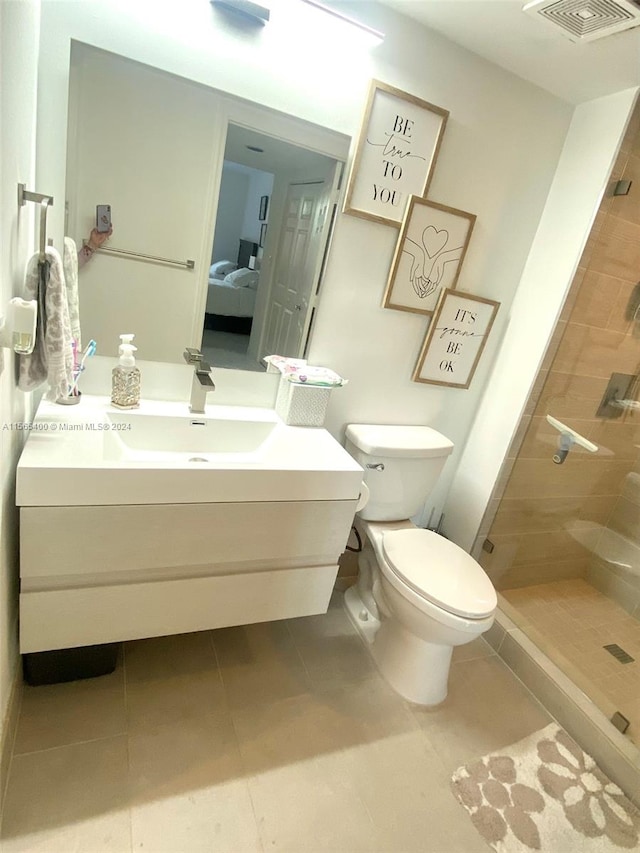 bathroom with vanity, tile floors, a tile shower, and toilet