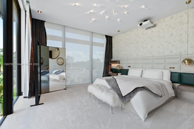 bedroom featuring light carpet, wallpapered walls, multiple windows, and floor to ceiling windows