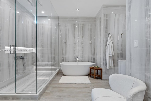 bathroom featuring a freestanding tub, a marble finish shower, and tile walls